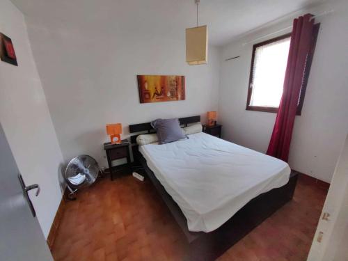 une chambre avec un lit avec des draps blancs et une fenêtre dans l'établissement Charmant T2 mezzanine climatisé avec piscine, proche plage et loisirs, pour 5 pers. - FR-1-607-77, au Cap d'Agde