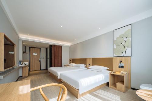 um quarto com uma grande cama branca e uma mesa em Parker Hotel Huangshan Tunxi Old Street Branch em Montanhas Huangshan