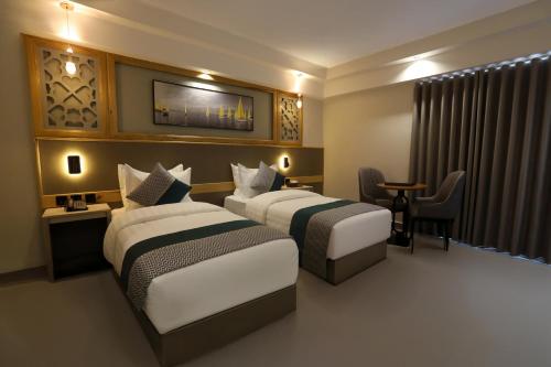 a hotel room with two beds and a table at Aroma Hotel in Aqaba