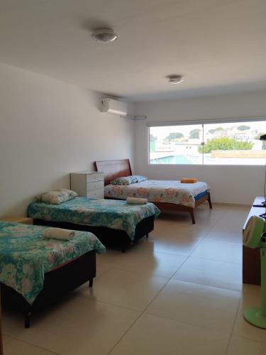 a room with three beds and a window at Estilo Suíte in São Paulo