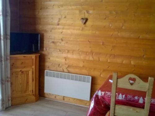 Cette chambre est dotée d'un mur en bois, d'un radiateur et d'une télévision. dans l'établissement Studio pour 3 avec balcon exposé Sud/Ouest, proche centre et remontées, parking privé - FR-1-676-73, à Châtel