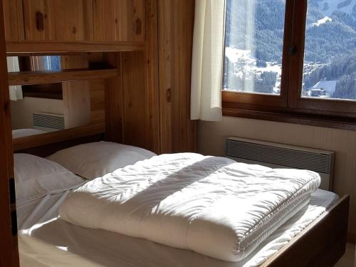un lit dans une chambre avec une fenêtre dans l'établissement Charmant 3 pièces à Châtel avec balcon, proche pistes et navettes, pour 6 personnes - FR-1-676-62, à Châtel