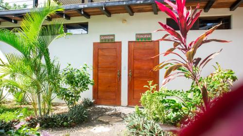 a building with wooden doors in a garden with plants at Four Trees Jungle Lodge in San Juan del Sur