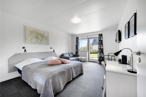 a white bedroom with a bed and a desk at Skovdal Kro in Jelling