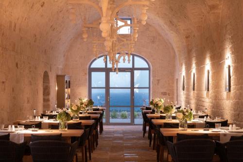 a dining room with tables and chairs and a large window at Masseria Auraterrae in Polignano a Mare