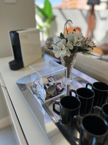 a glass tray with a vase with a bouquet of flowers at Cobertura 2Dorm Vista Mar e Serra in Capão da Canoa