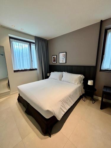 a bedroom with a large white bed with two windows at Hotel Stelvio Tirano in Tirano