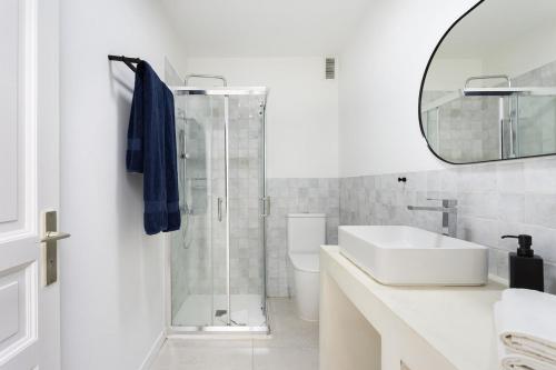 Un baño blanco con lavabo y espejo. en Eden Rentals Casa Salitre Neptuno Playa la Arena, en Puerto de Santiago