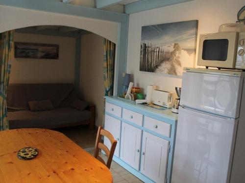 La cuisine est équipée d'une table et d'un réfrigérateur avec un four micro-ondes. dans l'établissement Studio cabine mezzanine 6 pers, terrasse, barbecue, parking privé - Marseillan-Plage - FR-1-326-403, à Marseillan