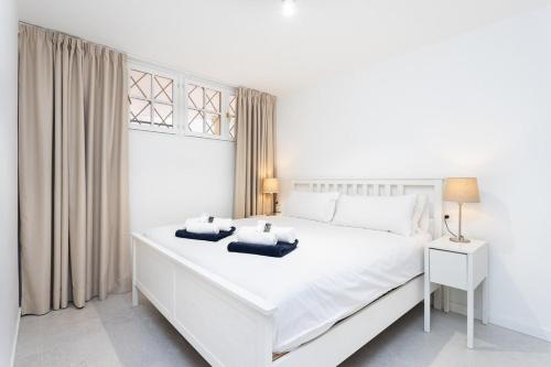 Un dormitorio blanco con una gran cama blanca y una ventana. en Eden Rentals Casa Salitre Neptuno Playa la Arena, en Puerto de Santiago