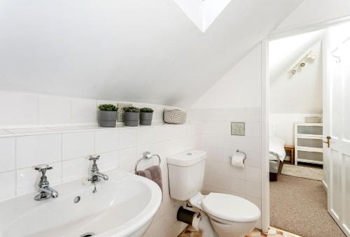 a white bathroom with a toilet and a sink at Bay View in Port Isaac
