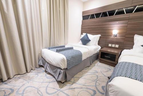 a hotel room with two beds and curtains at Sumou Hotel Al Khobar in Al Khobar