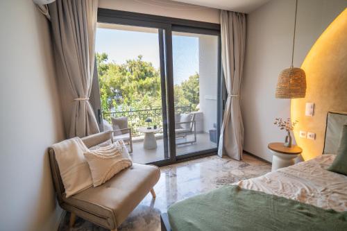 a bedroom with a bed and a chair and a balcony at East Blue Luxury Apartment in Kamári