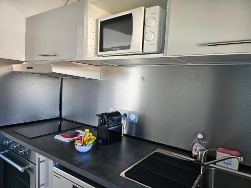 une petite cuisine avec un évier et un micro-ondes dans l'établissement LES PIEDS DANS L'EAU - Accès direct à la plage, à Bernières-sur-Mer