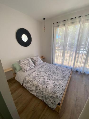 a bedroom with a bed and a large window at Joli mas bohème 60 m carré a seulement une minute à pied de la plage 4 personnes in Le Pradet
