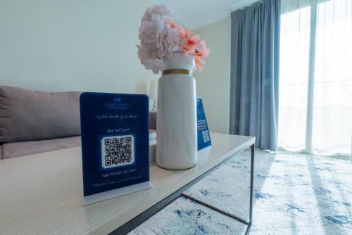 a vase with flowers and a book on a table at Sumou Hotel Al Khobar in Al Khobar