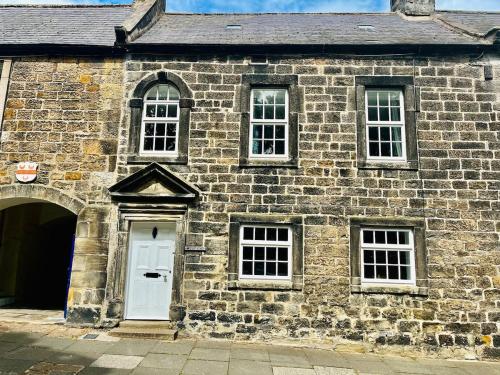 an old brick building with a white door and windows at Historic Rothbury Gem- West End House in Rothbury