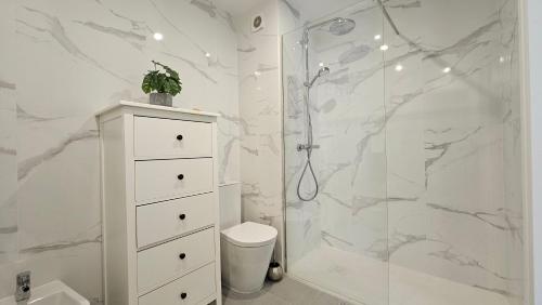 a white bathroom with a shower and a toilet at Casa Esmeralda, piscina, estacionamento, AC, Wifi in Olhão