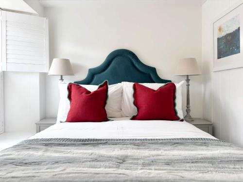 a bedroom with a large bed with red pillows at Quaint Cosy Cottage Mousehole in Mousehole