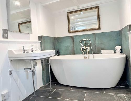 a bathroom with a white tub and a sink at Quaint Cosy Cottage Mousehole in Mousehole