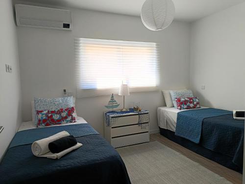 a bedroom with two beds and a window at Casa Esmeralda, piscina, estacionamento, AC, Wifi in Olhão