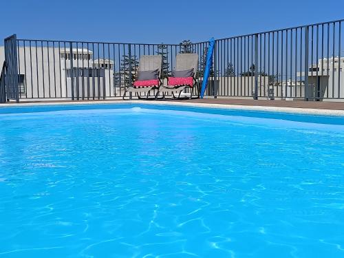 a swimming pool with two chairs and some water at Casa Esmeralda, piscina, estacionamento, AC, Wifi in Olhão