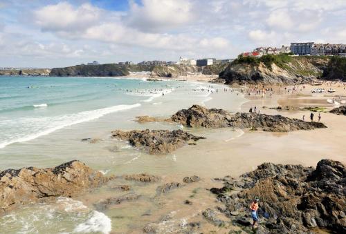 a group of people on a beach with rocks at Woodlands in Newquay