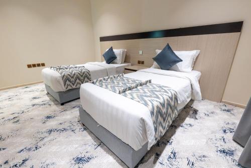 a hotel room with two beds and a couch at Sumou Hotel Al Khobar in Al Khobar