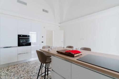 a kitchen with white cabinets and a counter with chairs at Ca' Rosa - Salento Selection in Acquarica del Capo