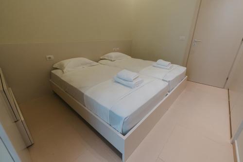 a white bed in a room with towels on it at MIKU Green Coast in Palasë