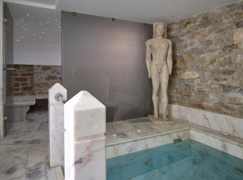 a statue of a man standing next to a swimming pool at Hotel Ploes in Ermoupoli