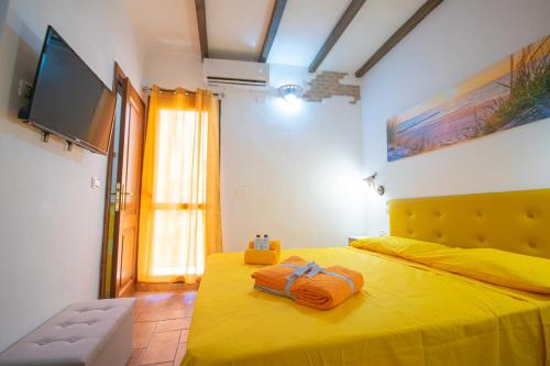 a bedroom with a yellow bed with towels on it at B&B Sinis Domus in Siniscola