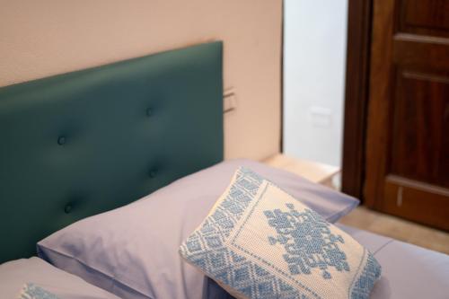 a bed with a green head board and a pillow at B&B Sinis Domus in Siniscola