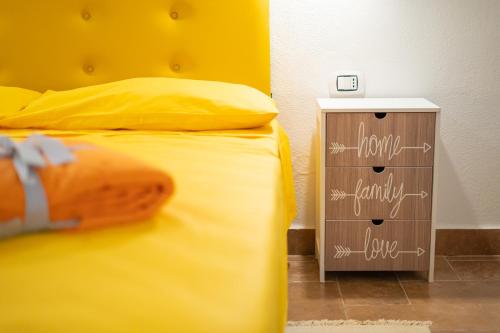a bedroom with a yellow bed and a night stand at B&B Sinis Domus in Siniscola