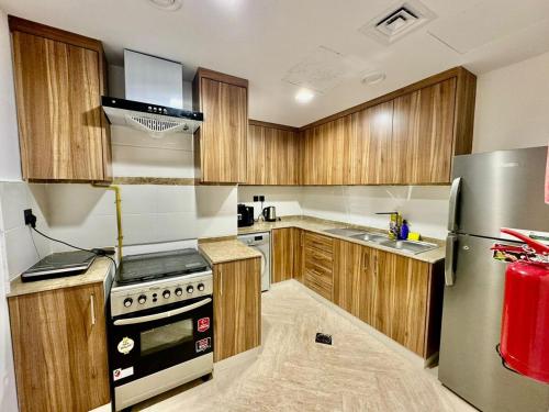 a kitchen with wooden cabinets and a stainless steel refrigerator at JSCOM Grand Residence ABU HAIL in Dubai