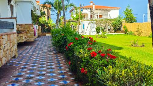 a garden path with red flowers and a house at L'unico - Sea View, Pool & Jaccuzi in Oued Laou