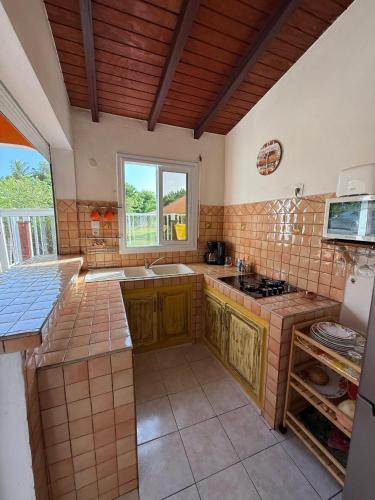 a large kitchen with a sink and a stove at Maison cosy à Saint-François avec piscine in Saint-François