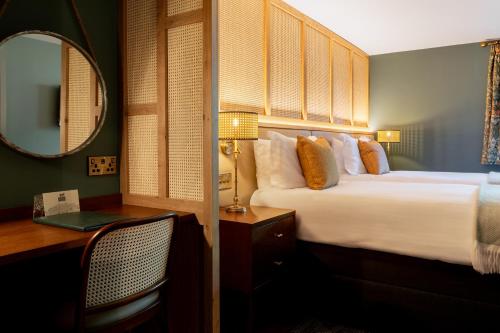 a bedroom with a bed and a desk and a mirror at The Hampshire Hog in Clanfield