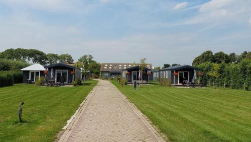 a walkway leading to a large yard with houses at Recreatie aan de Vecht, Hooibergje 2, Weesp in Weesp