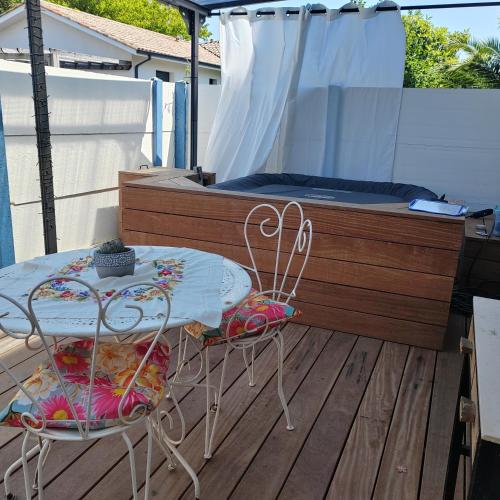 un tavolo e due sedie su un ponte con un letto di Petite maison mitoyenne, proche port & Arcachon a La Teste-de-Buch