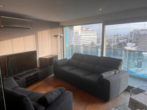 a living room with a couch and a flat screen tv at 2 Bed Apt in Ocean Village with Pools Jacuzzi Rock Views in Gibraltar