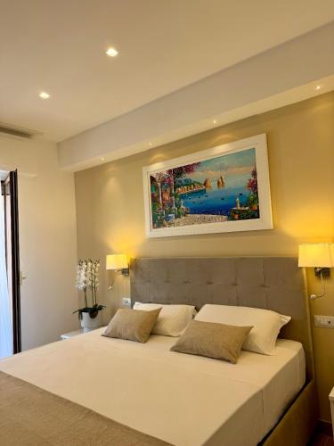 a bedroom with a white bed with a painting on the wall at Hotel Kali Sorrento in Sorrento