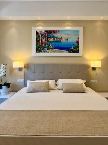 a bedroom with a large white bed with a painting on the wall at Hotel Kali Sorrento in Sorrento
