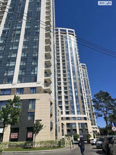 a tall building with a person walking in front of it at PREMIUM apartments ЖК Автограф, Институт сердца, МВЦ, Центр серця, Братиславская, Юность, Черниговская, Левобережная, Дарница in Kyiv