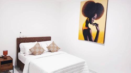 a bedroom with a bed and a painting on the wall at Appartement spacieux et cosy au coeur des 2 Plateaux in Abidjan