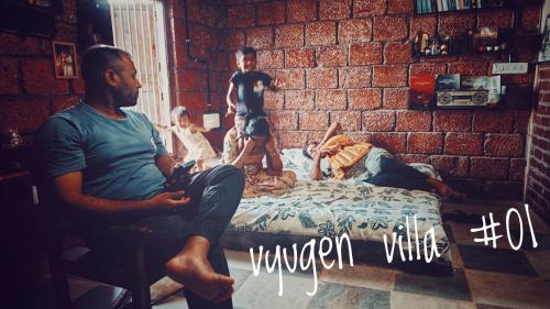 a man sitting on a bed with a group of people at Vyugen Villa #01 in Kāraikkudi