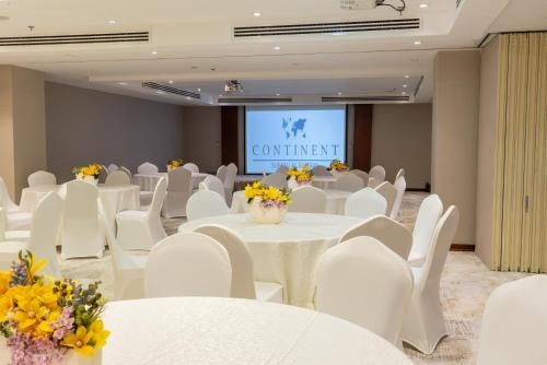 a conference room with white tables and white chairs and a screen at Sumou Hotel Al Khobar in Al Khobar