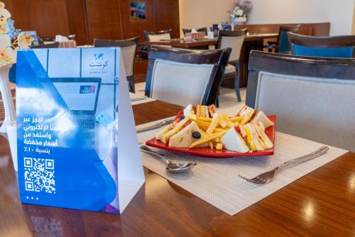 a plate of food and french fries on a table at Sumou Hotel Al Khobar in Al Khobar