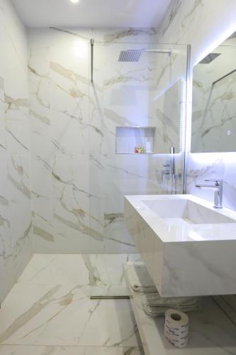 a white bathroom with a sink and a mirror at Hotel New York in Vlorë