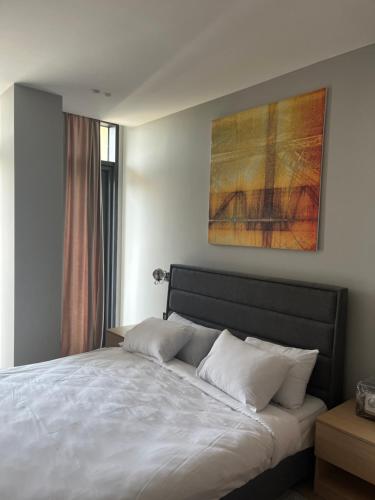ein Schlafzimmer mit einem weißen Bett und einem Gemälde an der Wand in der Unterkunft Sea Breeze Polo Residences - One bedroom apartment in Nardaran